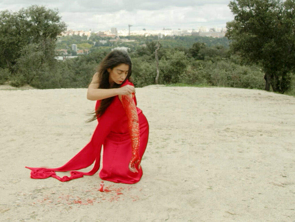 MONICA MURA vestida de rojo realizando la acción con merbromina